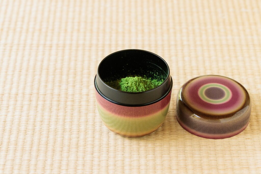 棗（なつめ）に抹茶が入った茶道具。畳の上に置かれた棗は、骨董品査定や茶道具買取で高評価されるポイントとなる保存状態や素材がわかる一品です。