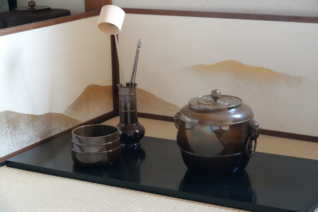 遠州流茶道具の基本的な設え。風炉先屏風と茶釜、建水、柄杓が整然と配置され、格式ある茶席の雰囲気を伝えている。遠州流に評価される道具の美意識と所作を感じさせる構図。