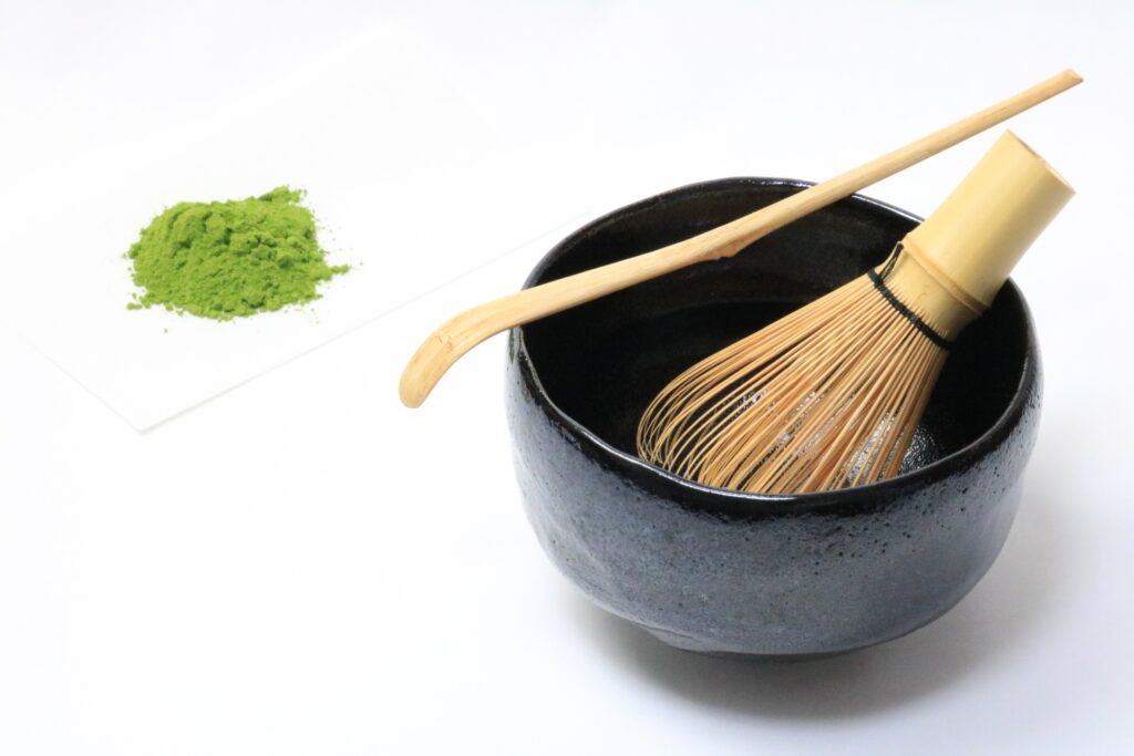 瀬戸黒風の黒釉茶碗と茶筅、抹茶が並んだ茶道具